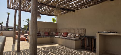 Terrasse sur le toit du Riad Arkaya à Essaouira avec pergola en bois, sièges confortables et palmiers sous un ciel bleu