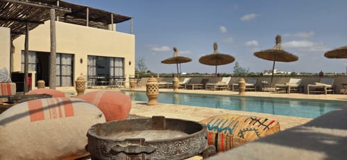 Piscine sur le toit du Riad Arkaya à Essaouira avec transats, parasols en chaume et vue sur l'océan