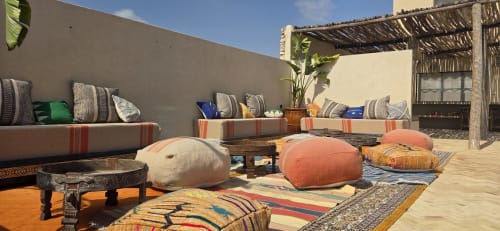 Lounge sur le toit du Riad Arkaya à Essaouira avec poufs colorés, tapis motifs et sièges confortables sous pergola