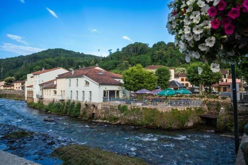 Maison Du Haut Salat, hôtel au bord de la rivière à Seix, France avec bâtiments blancs et parasols colorés