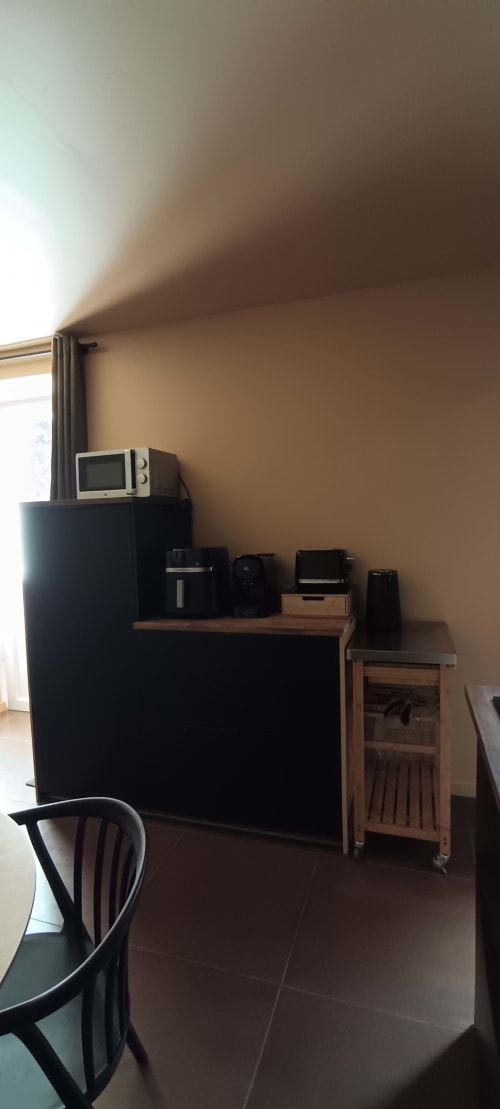 Kitchen area at Domaine Alga with microwave, appliances, wooden furniture, and window light in Bourg-Charente