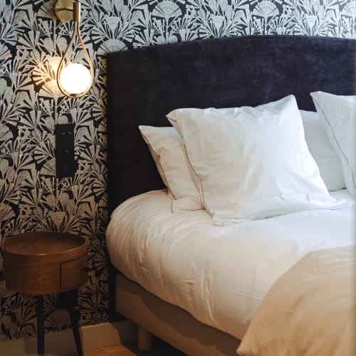 Chambre élégante à L'Ode à Pierre B&B à Dax avec tête de lit bleu marine, literie blanche et papier peint à motifs botaniques