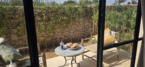 Vue du jardin du Riad Arkaya depuis la Chambre Mogador avec table ronde, sièges et plants de tomates à Essaouira