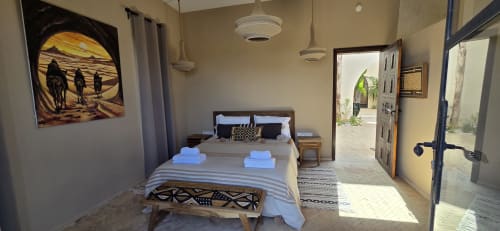 Chambre Beldi au Riad Arkaya à Essaouira avec lit rayé, portes donnant sur le jardin, œuvres d'art et décor traditionnel