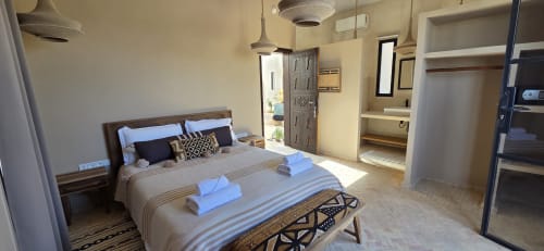 Chambre du Riad Arkaya à Essaouira avec vue sur le jardin, literie rayée, mobilier en bois et équipements modernes