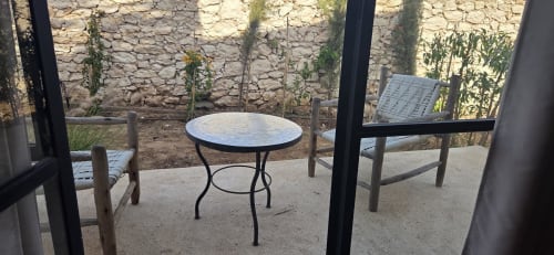 Espace terrasse du jardin du Riad Arkaya à Essaouira avec table ronde, chaises et murs en pierre