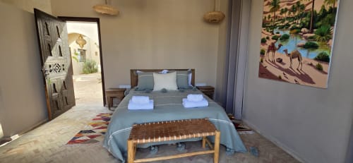 Chambre du Riad Arkaya à Essaouira avec lit bleu, porte traditionnelle et œuvres d'art du désert