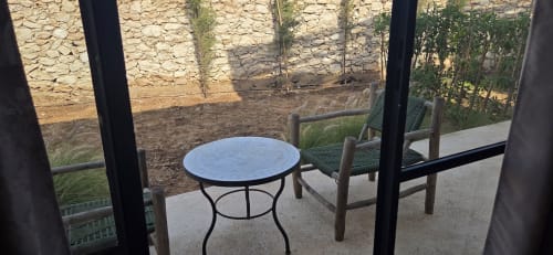 Table de bistrot bleue et chaises en bois sur la terrasse du Riad Arkaya à Essaouira, vue sur le jardin