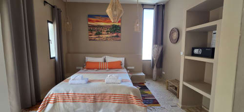 Chambre accessible au Riad Arkaya à Essaouira avec lit queen-size, accents orangés, rangements intégrés et vue sur la ville