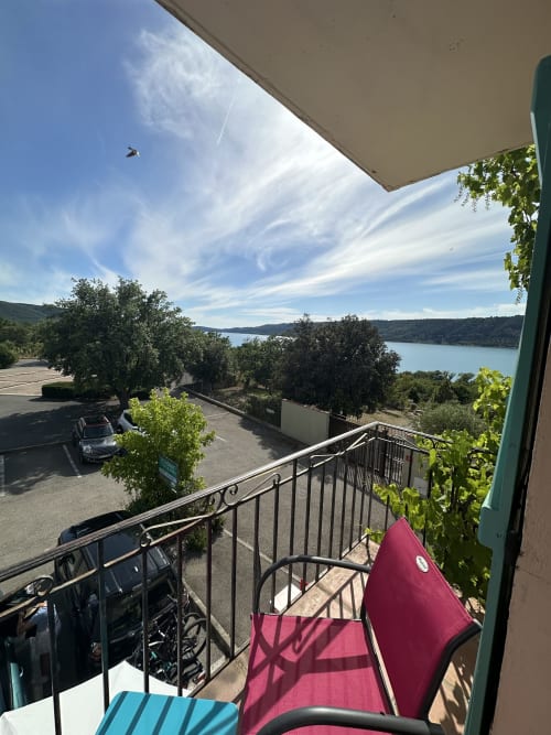 Vue depuis le balcon du lac turquoise à l'Hôtel Le Verdon, Les Salles sur Verdon avec chaise rose et paysage de collines pittoresque