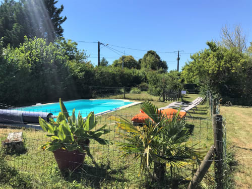 Piscine turquoise entourée de jardins luxuriants au gîte Domaine de Valmengaux à Vérac, France