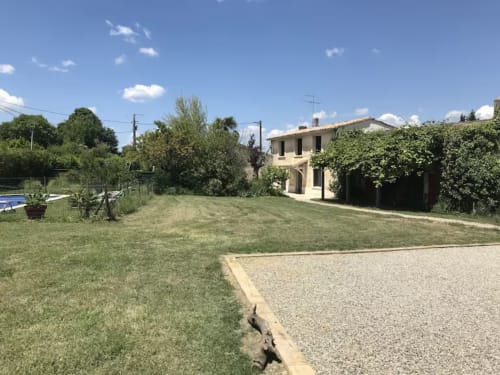 Charmant cottage de Vérac avec jardin luxuriant, allée et murs couverts de lierre sous un ciel bleu éclatant