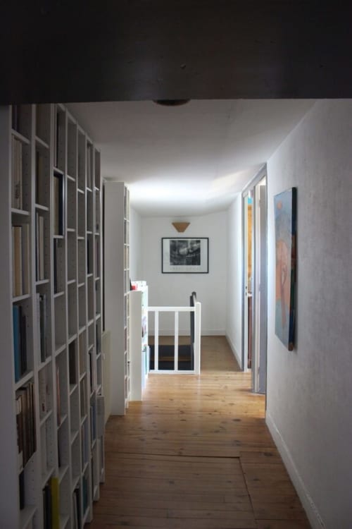Couloir lumineux aux parquets en bois, mobilier blanc et œuvres d'art du gîte Domaine de Valmengaux à Vérac