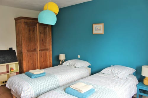 Deux lits jumeaux, murs turquoise et luminaires suspendus au cottage Les Petits Toits, Vérac