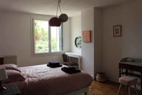 Chambre lumineuse du gîte Les Petits Toits à Vérac avec vue sur jardin, luminaires suspendus et parquet