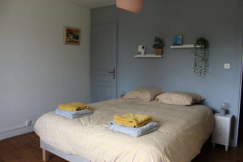 Chambre lumineuse du gîte Les Petits Toits avec lit bien fait, linge frais, plantes et vue sur le jardin à Vérac