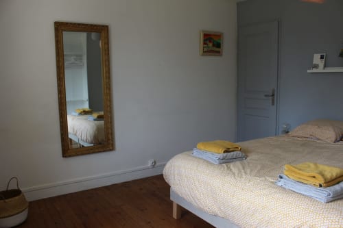 Chambre lumineuse du gîte Les Petits Toits à Vérac avec lits jumeaux, miroir et linges pliés prêts pour les hôtes