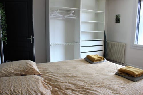 Chambre moderne avec penderie intégrée, serviettes pliées sur le lit, vue sur le jardin au gîte Les Petits Toits à Vérac, France