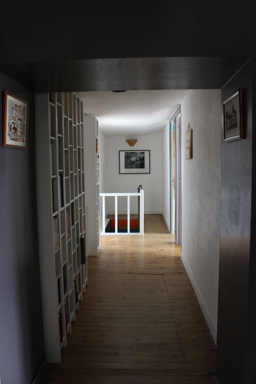 Long couloir aux portes grillagées blanches du cottage Les Petits Toits, parquet, barrière de sécurité blanche au fond