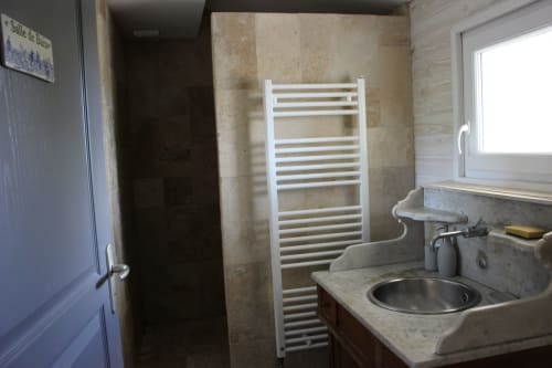 Salle de bains du gîte Les Petits Toits à Vérac avec lavabo, radiateur sèche-serviettes blanc et douche