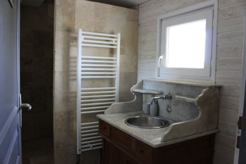 Salle de bains avec radiateur sèche-serviettes blanc, lavabo en marbre et fenêtre au gîte Domaine de Valmengaux, Vérac