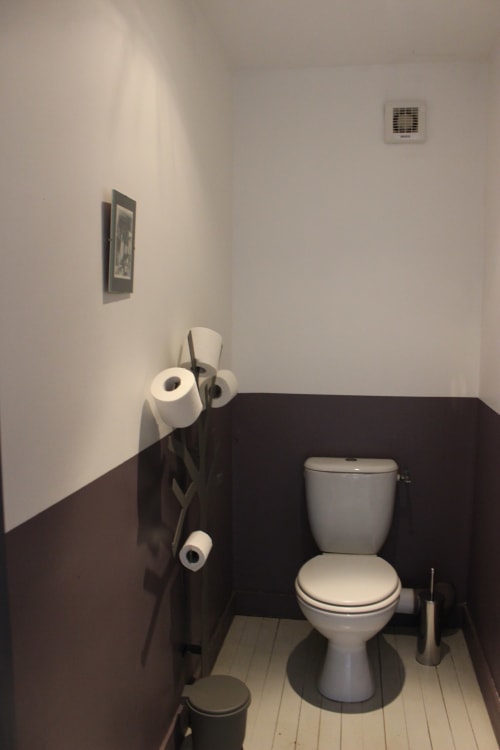 Salle de bains moderne avec toilettes, porte-serviettes et ventilateur au gîte Les Petits Toits à Vérac, France