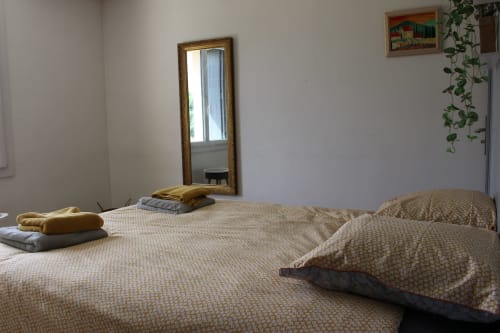 Chambre douillette du gîte Les Petits Toits à Vérac avec lits jumeaux, miroir à cadre bois et vue sur le jardin