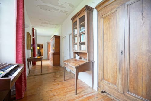 Élégant couloir du Domaine les Olivoux avec mobilier en bois, piano et armoires ornementées à Pomport.