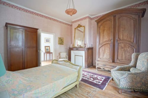 Chambre élégante au Domaine les Olivoux à Pomport avec mobilier en bois, papier peint rose et décor français classique