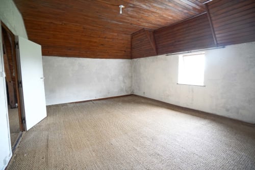 Chambre vide aux plafonds bois et murs beige du Domaine les Olivoux, Pomport