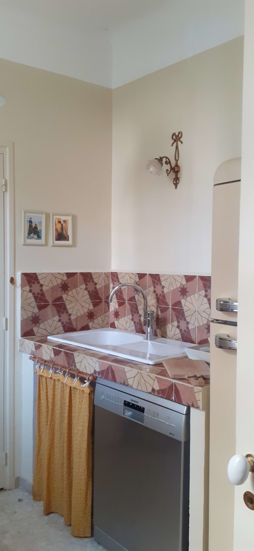 Kitchen sink with red patterned tile backsplash in La maison Au Coin De La Roquette cottage in Arles