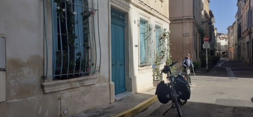 Charming street view of Au coin de la Roquette cottage in Arles with turquoise door and cyclist
