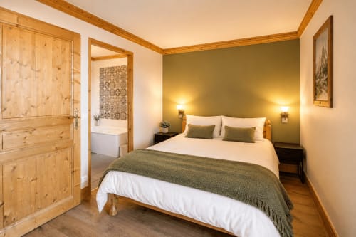 Chambre accueillante au Chalet du Vallon, La Plagne avec lit queen-size, mur d'accent vert, poutres apparentes et salle de bain attenante