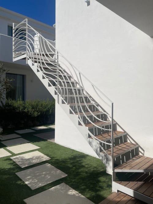 Moderna scala bianca con ringhiere metalliche curve che conducono al livello superiore dell'appartamento Like at Home Palau con vista giardino