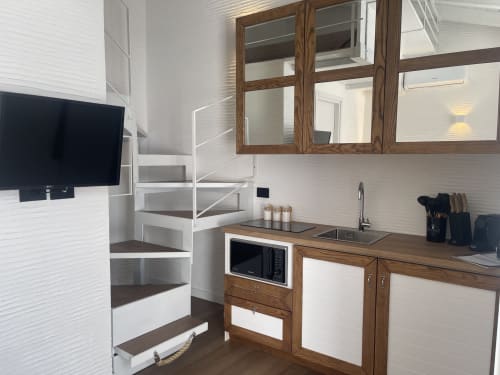 Cucina loft moderna con armadi in legno, piastrelle metro bianche e scala a spirale nell'appartamento di Palau
