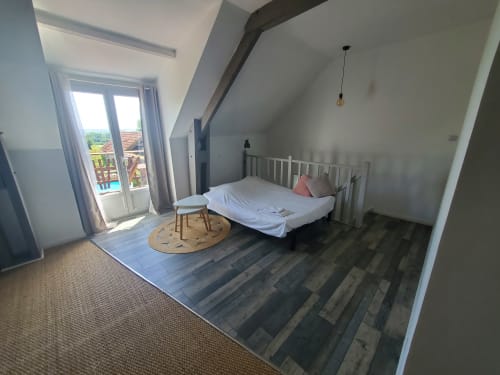 Modern attic bedroom at Le Panoramique cottage in Isigny-sur-Mer with white bed, wooden floors, and garden view balcony