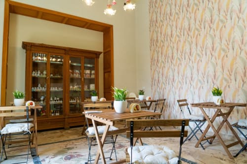 Sicily In Home apartment dining area with wooden tables, plants, and wallpapered walls in Catania