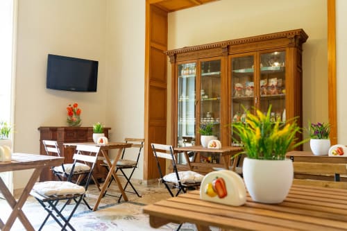 Elegant living room in Catania apartment with wooden furniture, TV, glass cabinet, dining area, and potted plants
