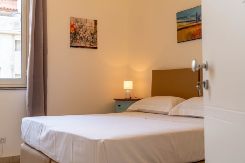 Cozy bedroom in DOMUS LAVICA apartment, Catania Sicily with white bed, bedside lamp, and city views