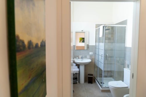 Modern bathroom in Catania apartment with pedestal sink, glass shower enclosure, and white toilet