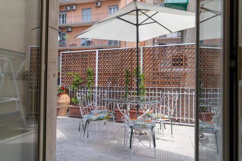 Terrace seating area with white umbrella, wrought iron chairs, and lattice privacy screens at Sicily In Home apartment in