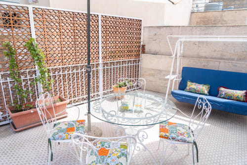 Sunny rooftop terrace at Sicily In Home, Catania with white wrought iron furniture, glass table, blue bench, and wooden