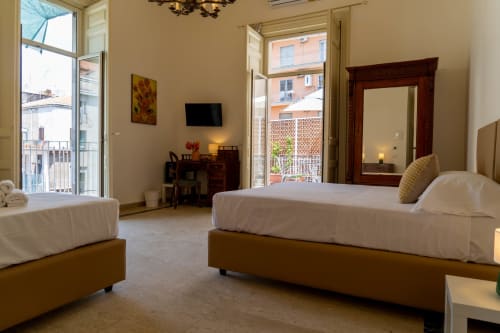 Spacious bedroom in Catania apartment with twin beds, city view balcony, TV, and modern amenities