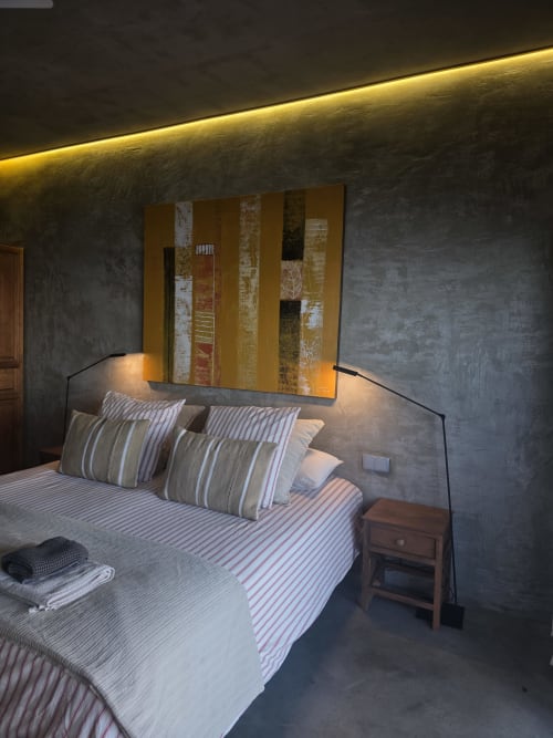 Quarto moderno do hotel Les Terrasses Les Suites em Calheta com roupa de cama listrada, obra de arte abstrata dourada e iluminação ambiente