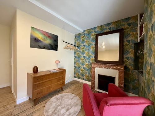 Élégant salon de cottage à Lourdes avec cheminée, canapé rouge, papier peint motifs, commode en bois et équipements modernes