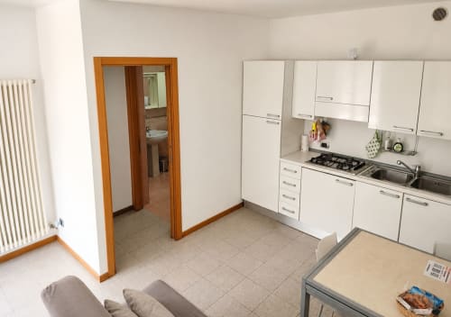 Cucina moderna e zona living nella villa Il Nido a Treviso con mobili bianchi, cucina a gas e open space