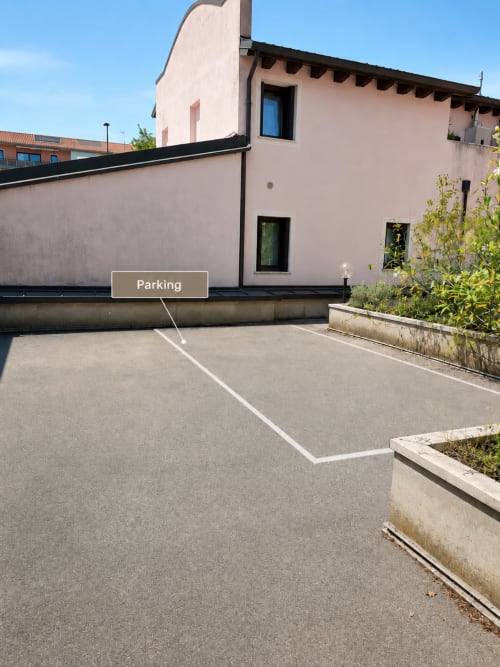 Parcheggio designato presso la villa Il Nido a Treviso con edificio rosa moderno e cortile paesaggistico