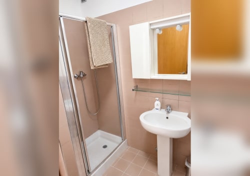Bagno moderno della villa Il Nido a Treviso con doccia, lavabo su piedistallo, specchio armadio e piastrelle beige