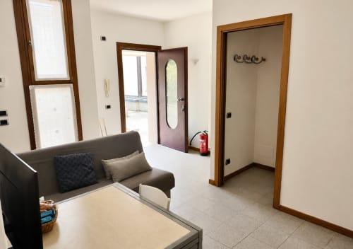 Soggiorno moderno nella villa Il Nido a Treviso con divano grigio, tavolo da pranzo e molteplici porte