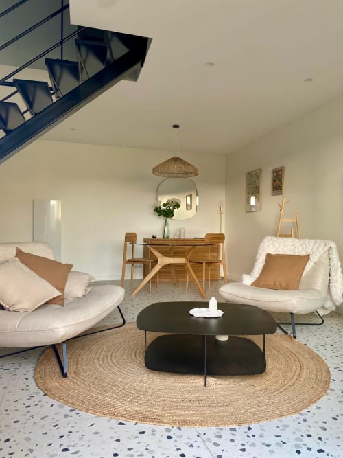 Salon moderne du gîte La Cour Tellier avec canapé crème, table basse noire, ensemble de salle à manger en bois et bleu